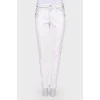 White jeans with a silver coating, with a tag