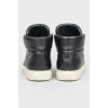Black leather sneakers with metallic brand logo