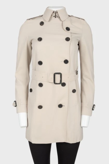 Beige trench coat with black buttons and belt
