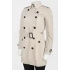 Beige trench coat with black buttons and belt